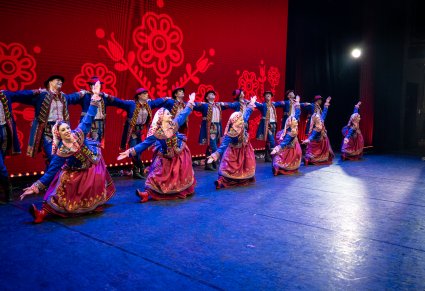 Grupa tancerzy w kostiumach podegrodzkich w tanecznych pozach na scenie