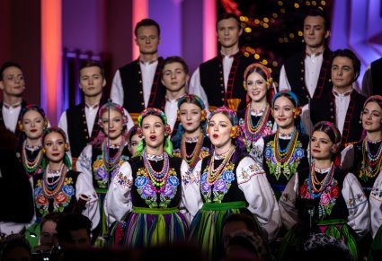 Na pierwszym planie dwie Artystki Chóru w kostiumach łowickich, w tle reszta część Artystów