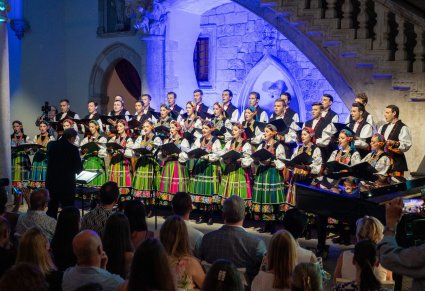 Cały chór w kostiumach łowickich a przed nim Mirosław Ziomek