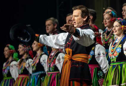 Zbliżenie na solistę chóru podczas koncertu z widocznych chórem w tle