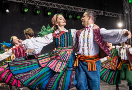 Pary Artystów w kostiumach opoczyńskich w trakcie wykonywania choreografii tanecznej na scenie