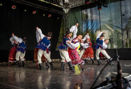 Pary Artystów w kostiumach limanowskich na scenie wykonujący choreografię taneczną