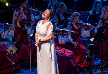 Zbliżenie na Solistkę w długiej białej sukni w tle Orkiestra