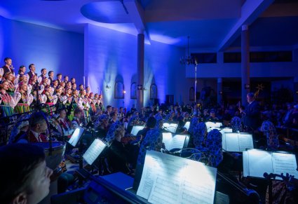 Boczny widok na Orkiestrę w kostiumach wilanowskich wraz z Dyrygentem- Dyrektorem zespołu "Mazowsze" i chór w kostiumach łowickich