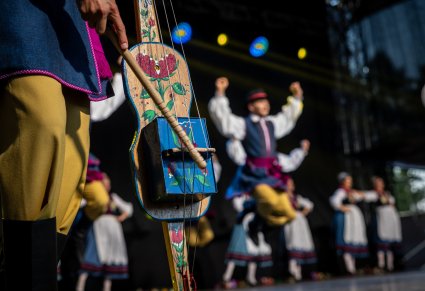 Zbliżenie na skrzypce diabelskie na scenie a w tle Artyści w kostiumach kaszubskich