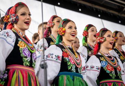 Zbliżenie na część Chóru w kostiumach łowickich w trakcie śpiewu na scenie