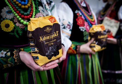 Artystka w kostiumie łowickim trzymająca paczkę pierników toruńskich