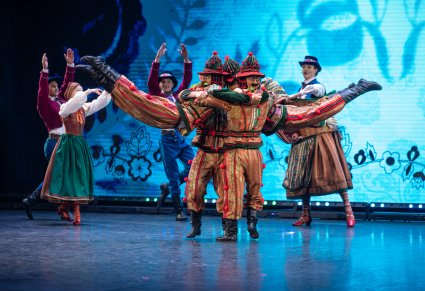 Na pierwszym planie wilamowickie pajace w trakcie wykonywania choreografii tanecznej, w tle Artyści wraz z wilamowicką Babą