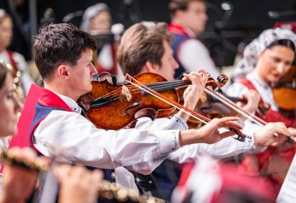 Zbliżenie na muzyka orkiestry, grającego na instrumencie smyczkowym