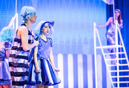 Na pierwszym planie smutne postaci Trójkątów w niebieskich kostiumach, w tle na drabinie Gwiazda w srebrnym kostiumie