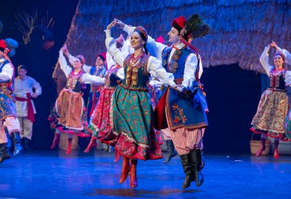 Pary Artystów w kostiumach krakowskich podczas wykonywania choreografii tanecznej na scenie