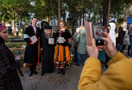 Para Artystów w kostiumach łowickich robiąca sobie zdjęcia z uczestniczką 51 kwesty na Starych Powązkach