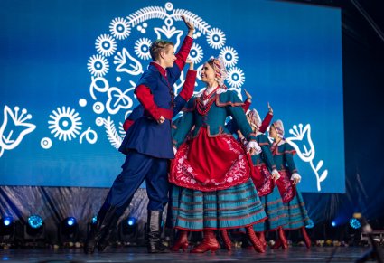 Na pierwszym planie para Artystów w kostiumach kujawskich a za nimi reszta par na scenie w choreografii tanecznej