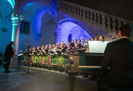 Na pierwszym planie akompaniator a w tle widzimy Mirosława Ziomka wraz z chórem w kostiumach łowickich