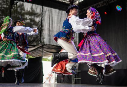 Dwie pary Artystów w kostiumach limanowskich wykonujący skoczną choreografię taneczną