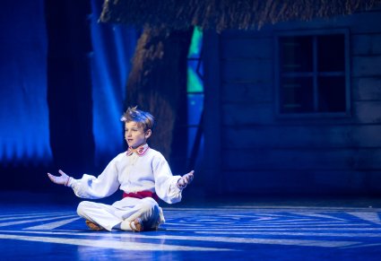 Zbliżenie na postać Małego Józka, który siedzi po turecku na scenie