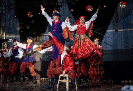 Artyści na scenie w kostiumach sieradzkich w trakcie wykonywania spektakularnej figury tanecznej