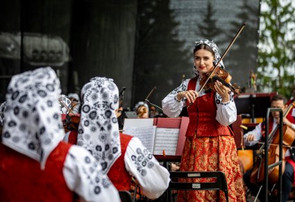 Skrzypaczka trzymająca skrzypce zwrócona w stronę innych skrzypaczek