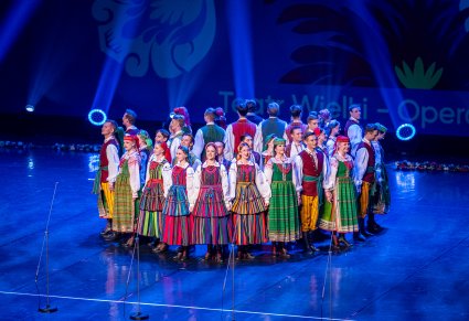 Artyści w kostiumach ludowych podczas wykonywania choreografii tanecznej na scenie