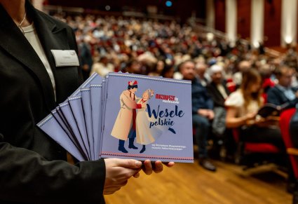Zbliżenie na katalogi a w tle widoczna publiczność