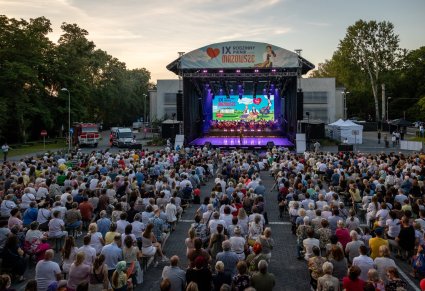 Widok na główną scenę plenerową i na Publiczność. Na scenie konferansjer, Orkiestra w kostiumach wilanowskich wraz z Dyrektorem zespołu "Mazowsze", który dyryguje koncert