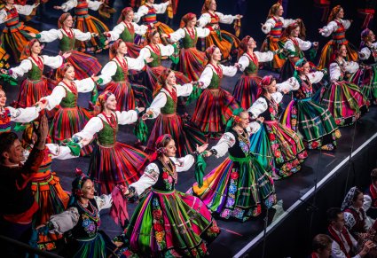 Na scenie Artyści w kostiumach ludowych podczas wykonywania choreografii tanecznej