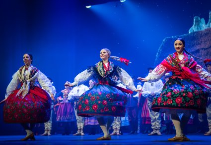Trzy Artystki w kostiumach krakowskich w trakcie wykonywania choreografii tanecznej