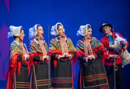 Na scenie artyści w tańcach wielkopolskich w z przyśpiewkami  - Świnorz. Cztery kobiety śpiewają, a mężczyzna gra na koźle wielkopolskim.