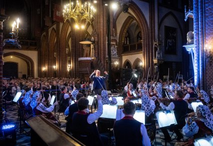 Orkiestra w szerokim ujęciu w kościele a przed nią dyrygent