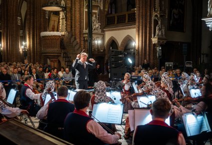 Orkiestra w szerokim ujęciu w kościele a przed nią dyrygent