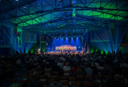 Szerokie ujęcie na wnętrze hali, scenę, zespól oraz zgromadzoną publiczność