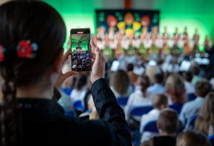 zbliżenie na obraz w telefonie, na którym widać chór i widownię