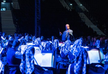 Orkiestra i dyrygent podczas koncertu uchwycona wraz z tłumem zgromadzonej publiczności