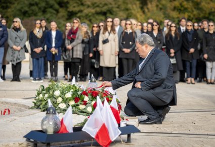 Dyrektor Mazowsza Jacek Boniecki poprawia szarfę na wieńcu