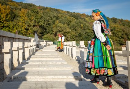 Artystka Mazowsza w kostiumie łowickim stoi przed jednym z grobów