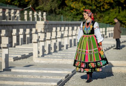 Artystka Mazowsza w kostiumie łowickim stoi przed jednym z grobów