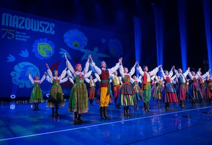 Artyści w kostiumach ludowych podczas wykonywania choreografii tanecznej na scenie