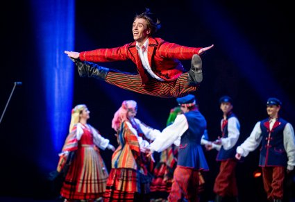 Na pierwszym planie Tancerz w kostiumie sieradzkim wykonujący w górze sznurek