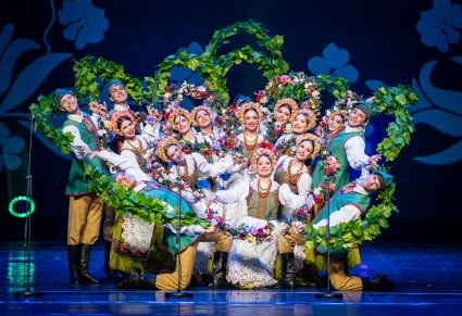 Na scenie Artyści w kostiumach lubuskich w trakcie wykonywania figury tanecznej z elementami dekoracji