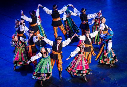 Artyści w kostiumach łowickich podczas wykonywania choreografii tanecznej na scenie