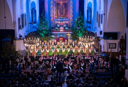 Widok z góry na całą przestrzeń kościelną, publiczność, Artyści Chóru w kostiumach łowickich wraz z orkiestrą