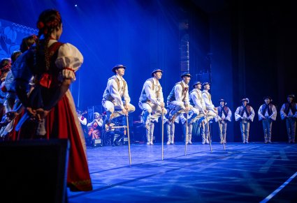 Na pierwszym planie Artyści w kostiumach podhalańskich w trakcie wykonywania choreografii tanecznej z kijkami