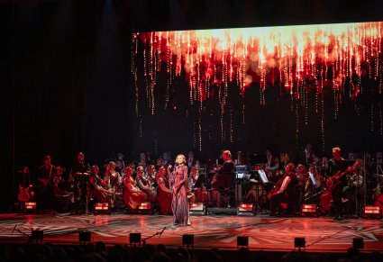 Anna Wyszkoni na środku sceny w czerwonej, długiej sukni a za nią Orkiestra w kostiumach wilanowskich z Dyrektorem Jackiem Bonieckim