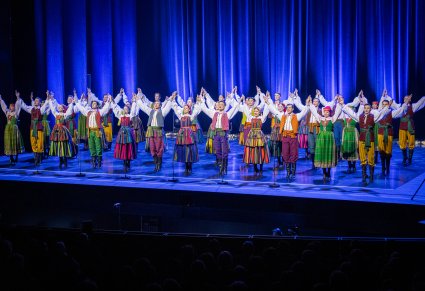 Grupa Artystów w kostiumach ludowych na scenie podczas wykonywania choreografii tanecznej