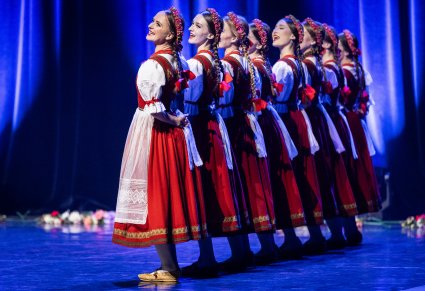 Artystki w kostiumach jurgowskich ustawione w rzędzie na scenie w trakcie wykonywania choreografii tanecznej