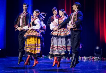 Zbliżenie na trzy pary w kostiumach krzczonowskich na scenie w trakcie wykonywania choreografii tanecznej