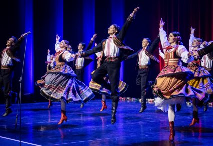 Pary Artystów w kostiumach krzczonowskich na scenie w trakcie wykonywania choreografii tanecznej