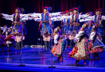 Grupa Artystów w kostiumach krakowskich w trakcie wykonywania choreografii tanecznej