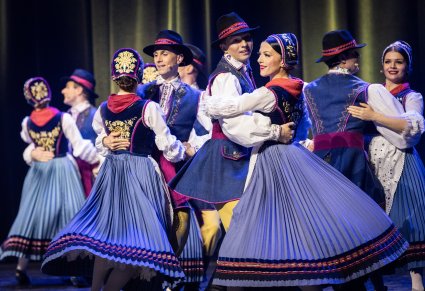 Pary Artystów na scenie w kostiumach kaszubskich w trakcie wykonywania choreografii tanecznej