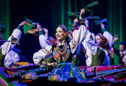 Zbliżenie na kręcącą się Artystkę na scenie w kostiumie łowickim